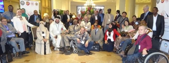 A large group of participants, several of them wheelchair users, gathered for a group photograph.