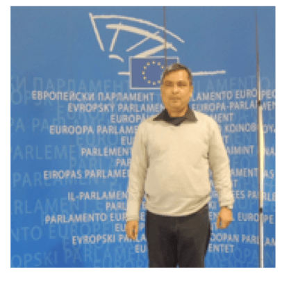 A man standing in front of a European Parliament backdrop.